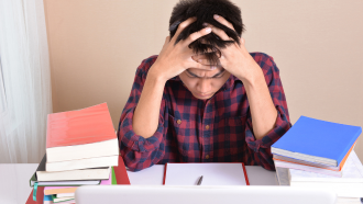 Stressed-out student facing a pile of homework.