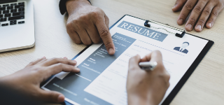 Close up of two pairs of hands gesturing at a resume.