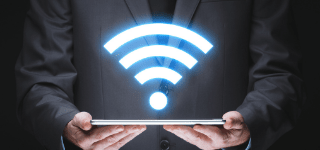 Figure in a suit holding a tablet. A glowing WiFi symbol emanates from the tablet.