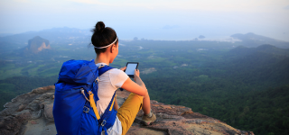 Hiker reading on their tablet while they take a rest.